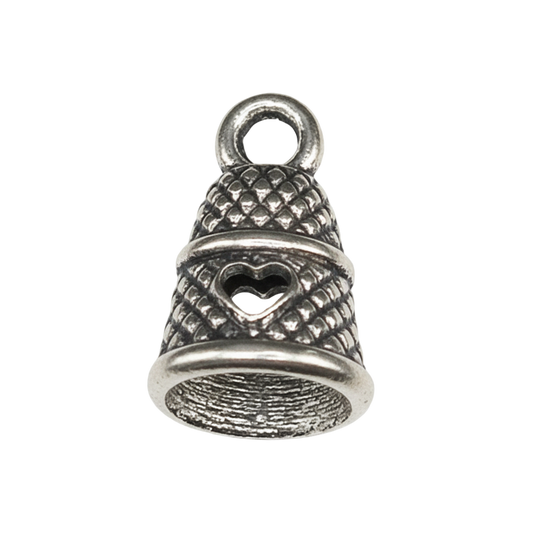 close-up of silver thimble charm with heart detail on black background