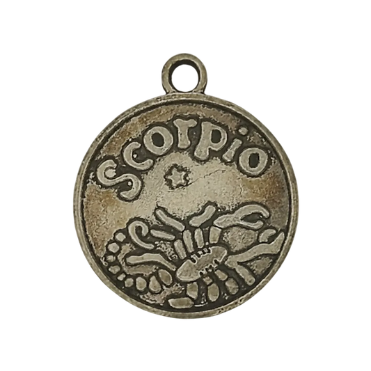 close-up of round metal charm reading 'scorpio' with scorpion design on black background