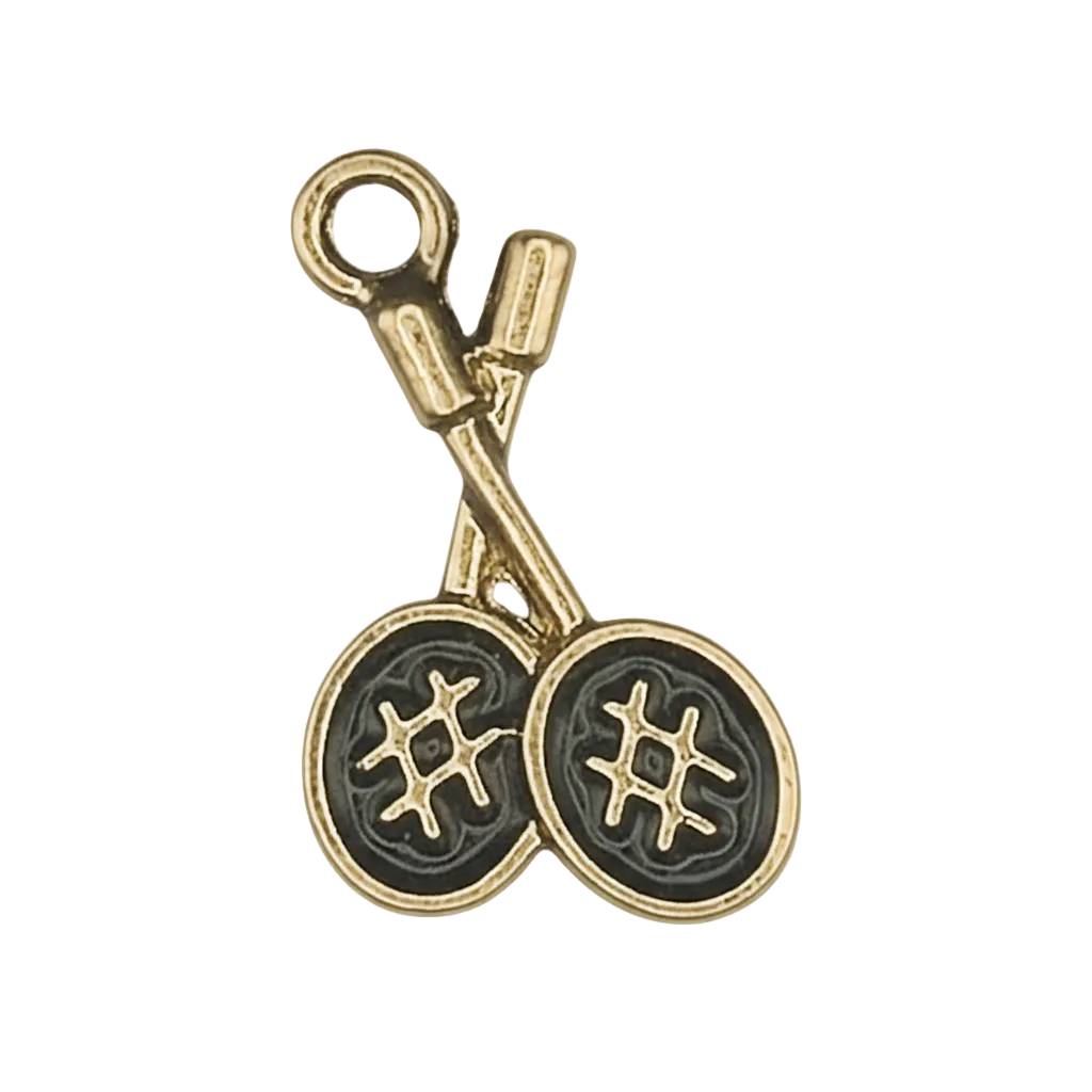 Close-up of a gold-tone charm shaped like crossed knitting needles with two yarn balls on a black background.