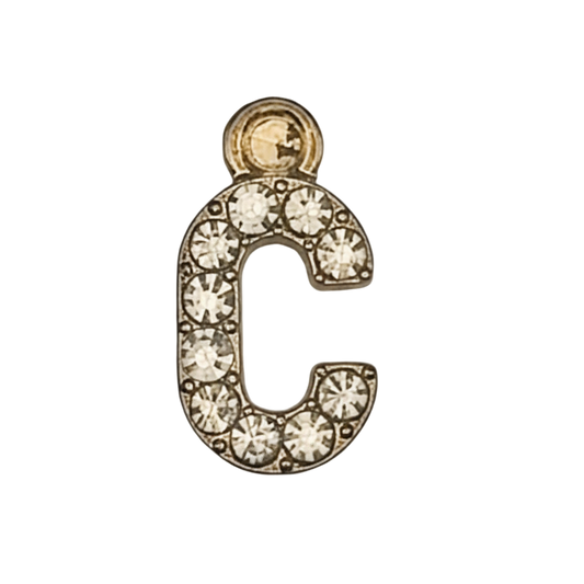 close-up of gold-tone letter C charm with clear stones on black background