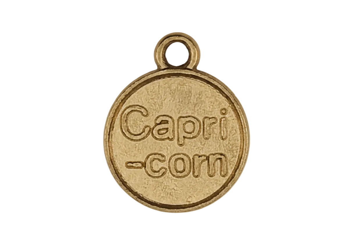 close-up of a gold round charm engraved 'Capri-corn' on a black background