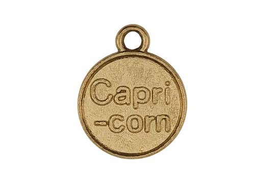 close-up of a gold round charm engraved 'Capri-corn' on a black background