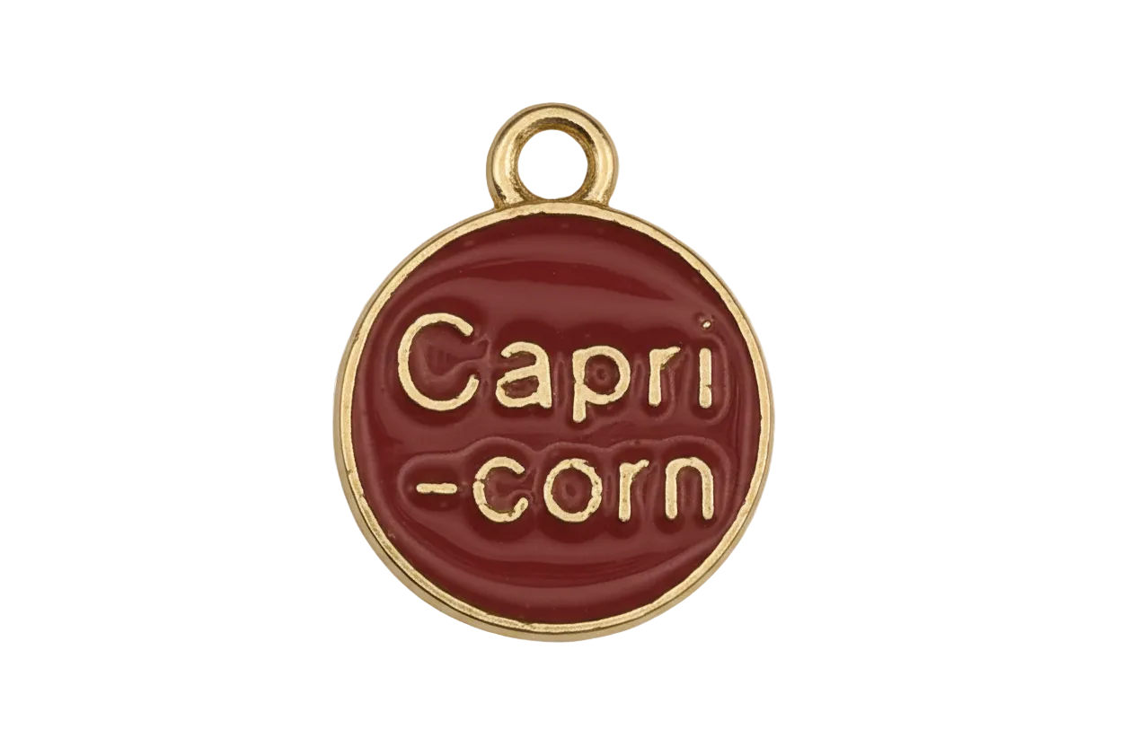 Close-up of a round red charm reading 'Capri-corn' with a gold-tone edge.