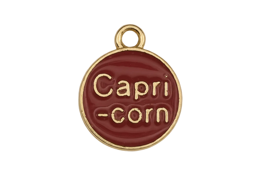 Close-up of a round red charm reading 'Capri-corn' with a gold-tone edge.