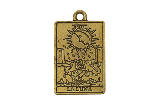 Close-up of rectangular gold-tone La Luna tarot charm with moon and dogs engraving.