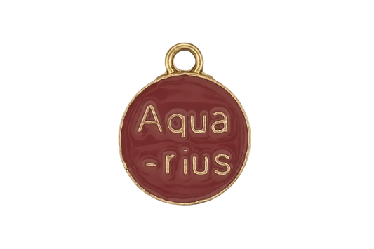 close-up of a small round red enamel charm with gold text reading “Aqua-rius.”