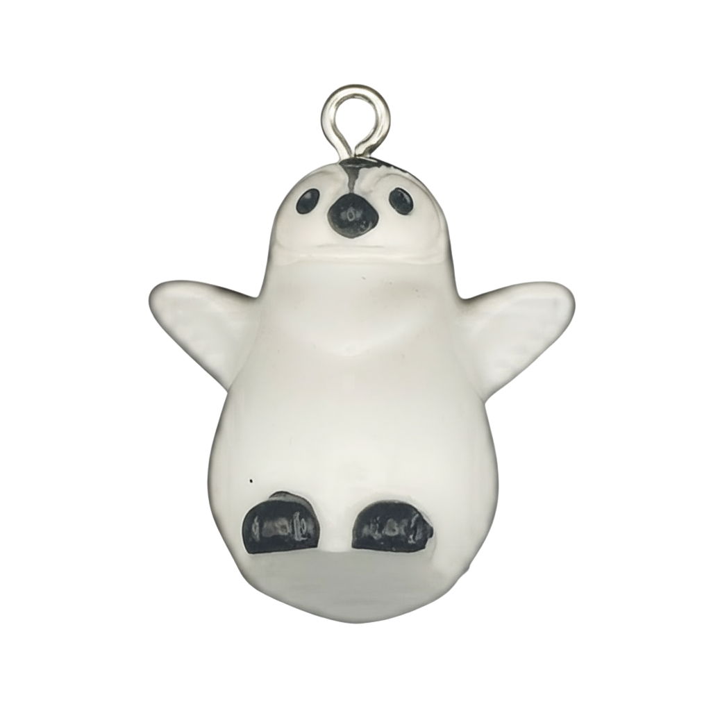 close-up of small white penguin chick charm with black beak and feet on a black background