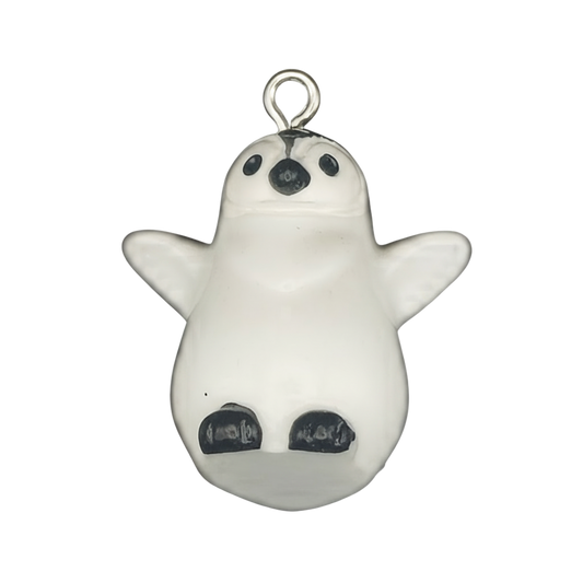 close-up of small white penguin chick charm with black beak and feet on a black background