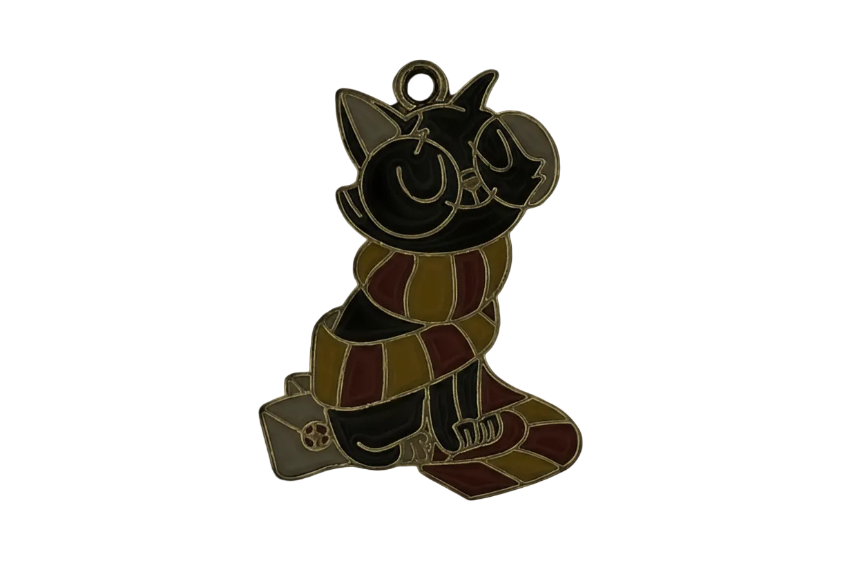 Close-up of black enamel cat charm with red and yellow striped scarf and glasses, gold-tone outline, on a black background.