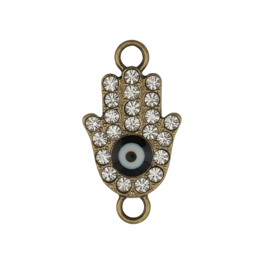close-up gold-tone rhinestone hamsa hand charm with black-and-white eye on black background