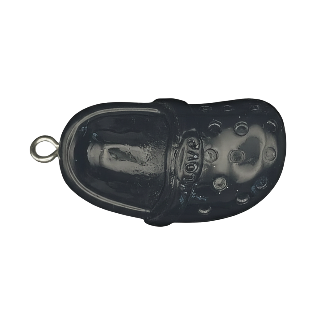 close-up of black clog shoe charm with 'love' text on strap, on dark background