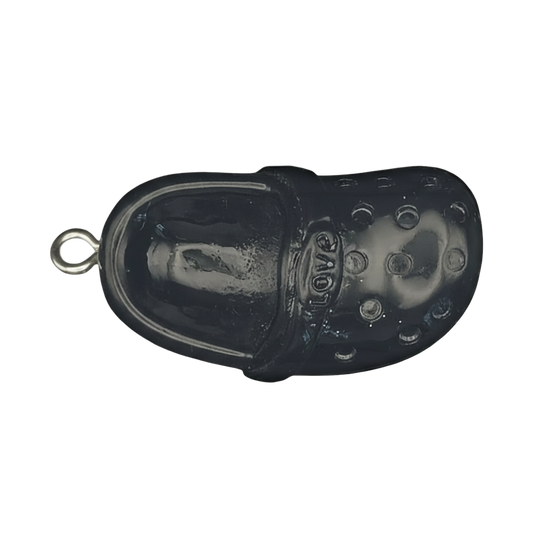 close-up of black clog shoe charm with 'love' text on strap, on dark background