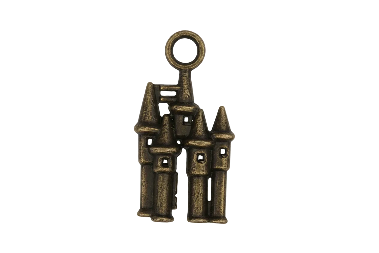 Close-up of a small bronze castle charm with turrets on a black background.