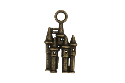 Close-up of a small bronze castle charm with turrets on a black background.