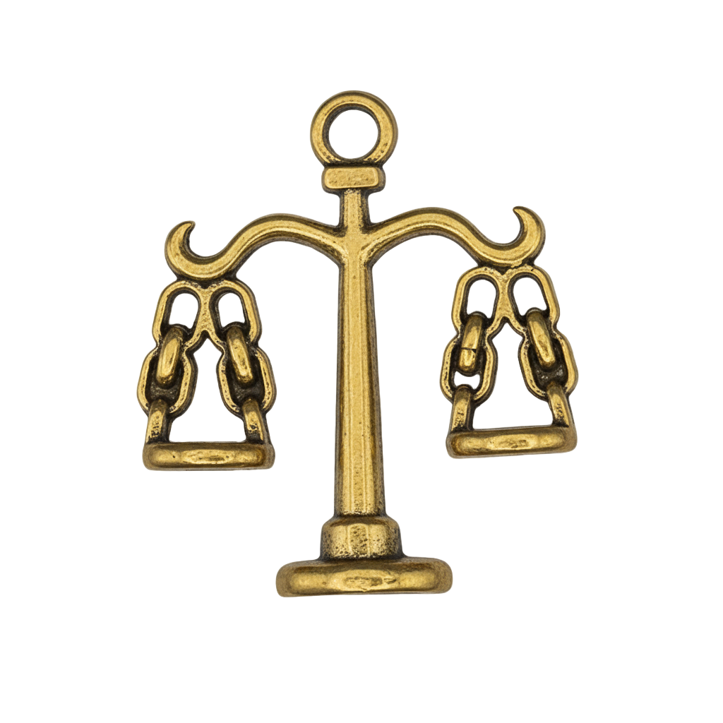 close-up of small gold scales charm on black background