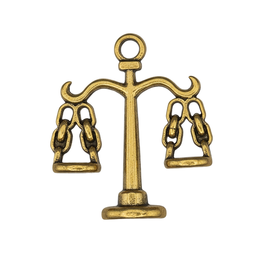 close-up of small gold scales charm on black background