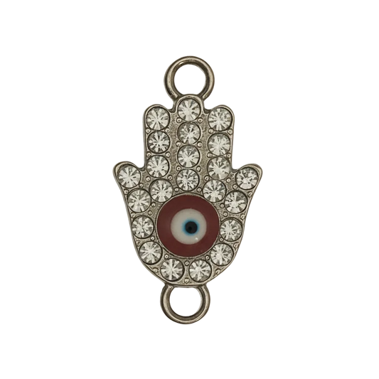 close-up of a rhinestone Hamsa hand charm with a red evil eye center on a black background