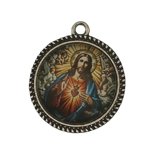 close-up of round charm with sacred heart icon and beaded edge on black background