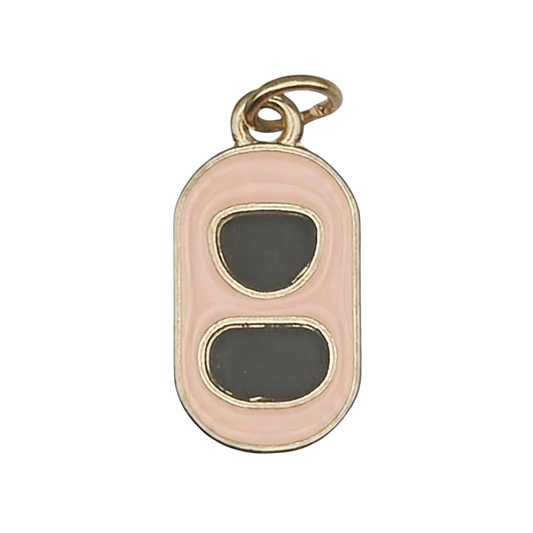 Close-up of a gold-tone soda can tab charm with pink border and black enamel ovals.