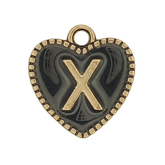 close-up of a heart-shaped charm with a raised gold letter X and dotted border on a dark background