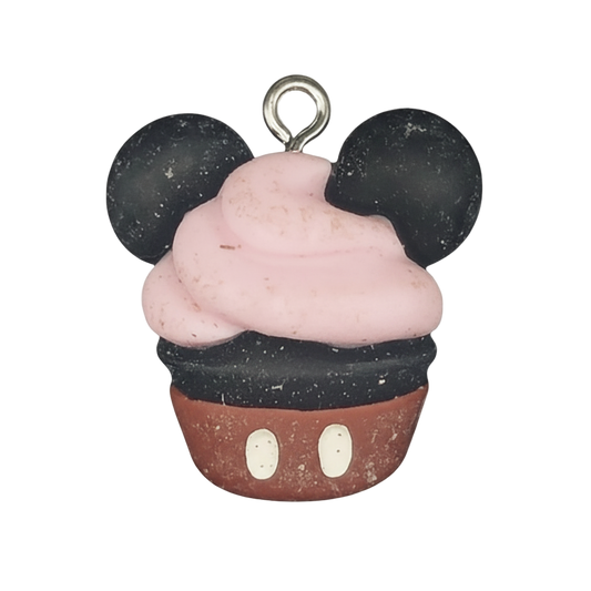 close-up of cupcake charm with mouse ears, pink frosting, and red base on a black background