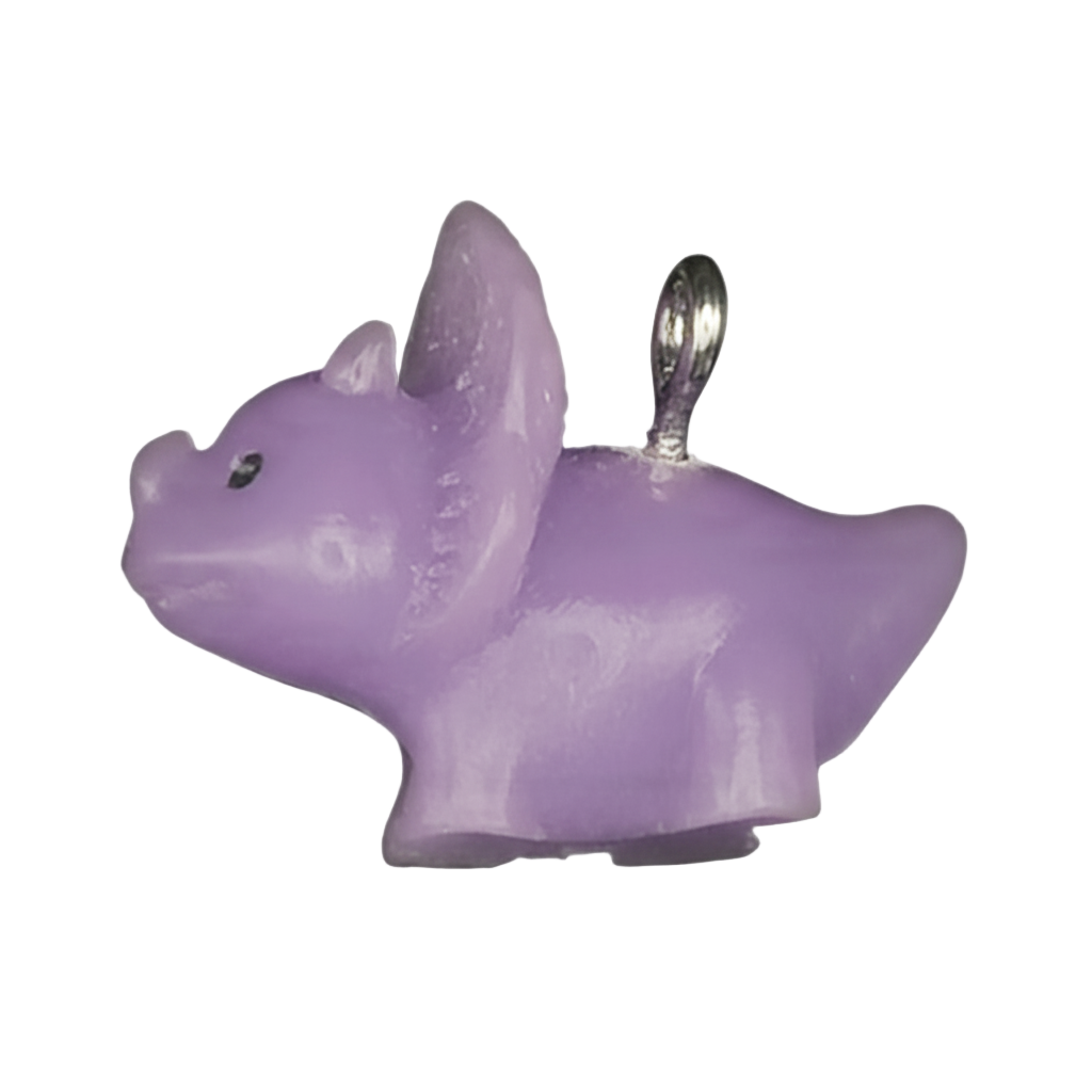 close-up of a small lilac dog-shaped charm with a silver-tone ring on a black background