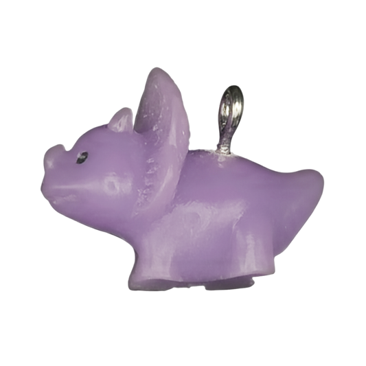 close-up of a small lilac dog-shaped charm with a silver-tone ring on a black background
