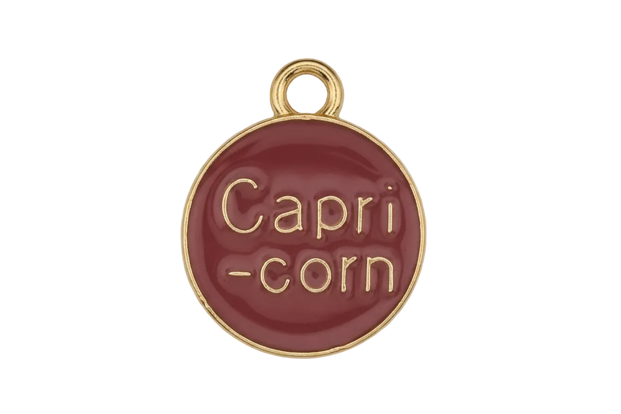 close-up of round red charm with gold 'Capri-corn' text on black background