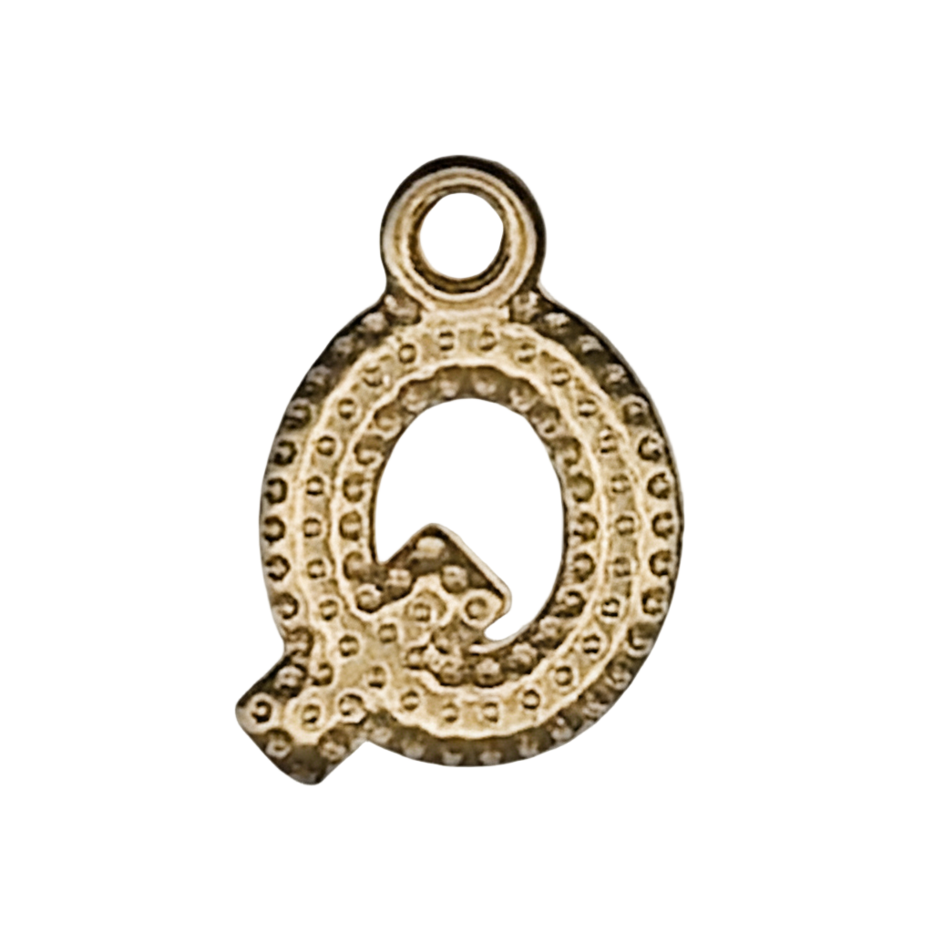 close-up of small gold letter Q charm on black background