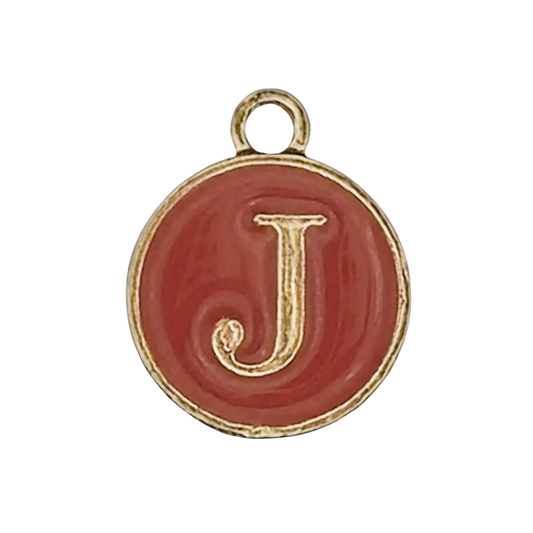close-up of a round red enamel charm with a gold letter J and gold-tone rim on a black background