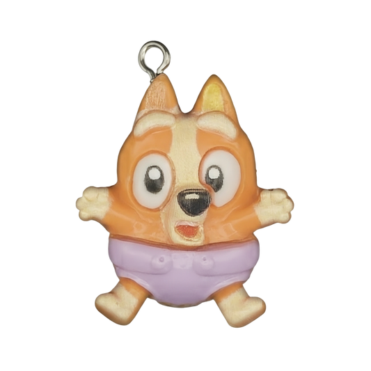 Close-up of orange cartoon puppy charm wearing a purple diaper on a black background.
