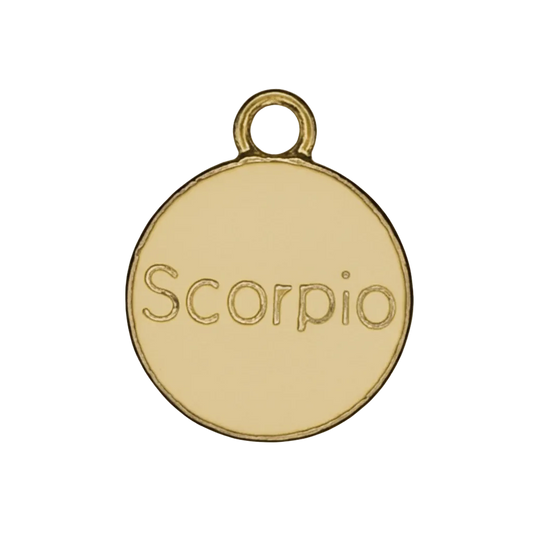 Close-up of a gold round charm engraved with the word Scorpio on a black background.