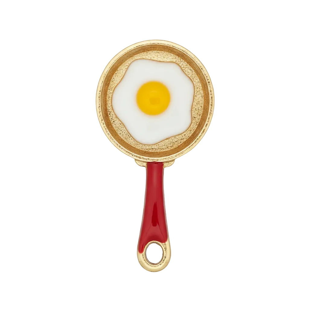 close-up of a gold-tone frying pan charm with a fried egg and red handle on black background