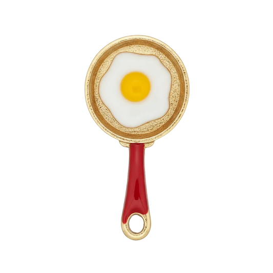 close-up of a gold-tone frying pan charm with a fried egg and red handle on black background