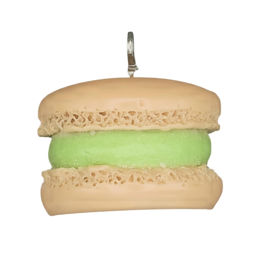 close-up of tan macaron charm with green filling on a black background