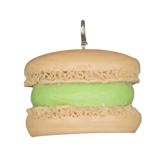 close-up of tan macaron charm with green filling on a black background