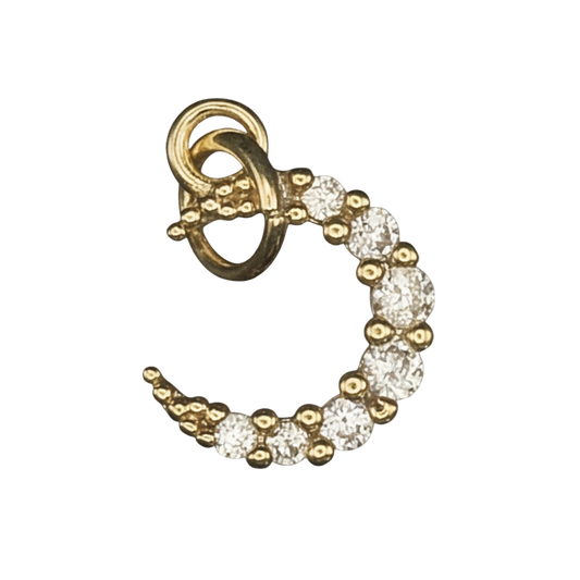 close-up of a small gold crescent moon charm with clear pavé stones on a black background