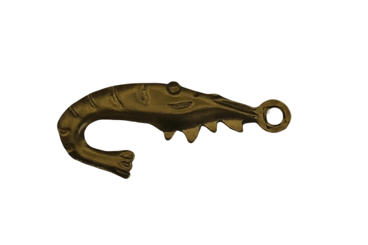 Close-up of a gold-tone shrimp-shaped charm on a black background.