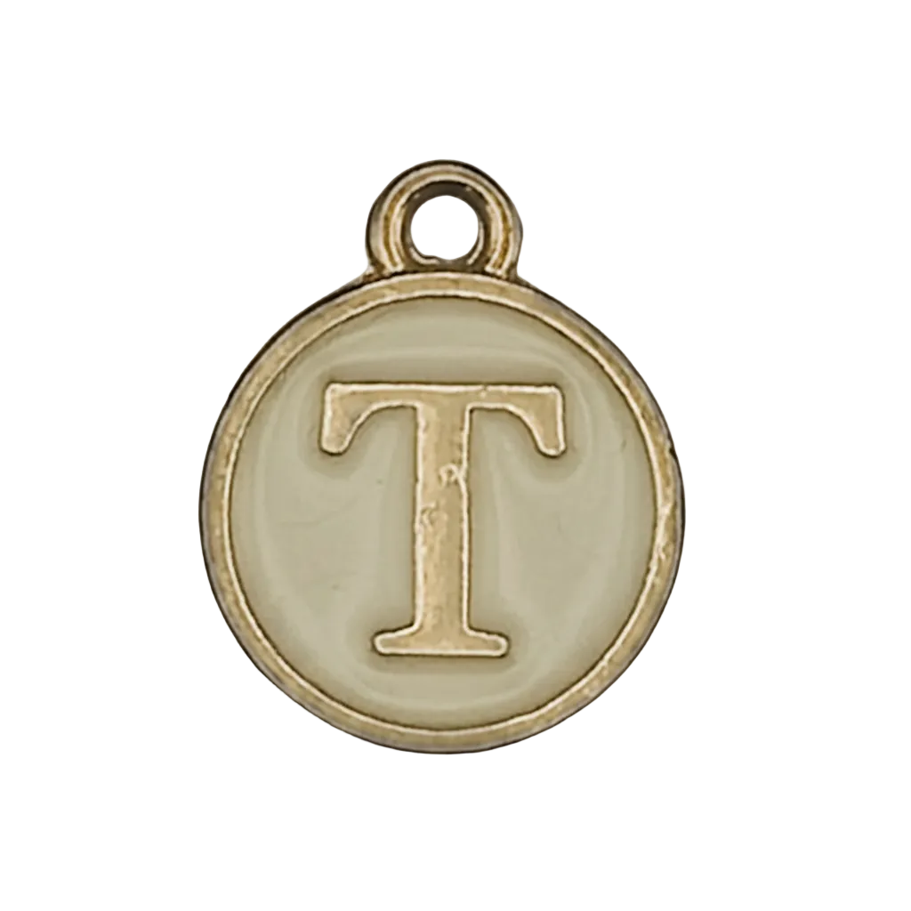 close-up of round gold-tone charm with letter T on cream background