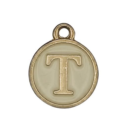 close-up of round gold-tone charm with letter T on cream background
