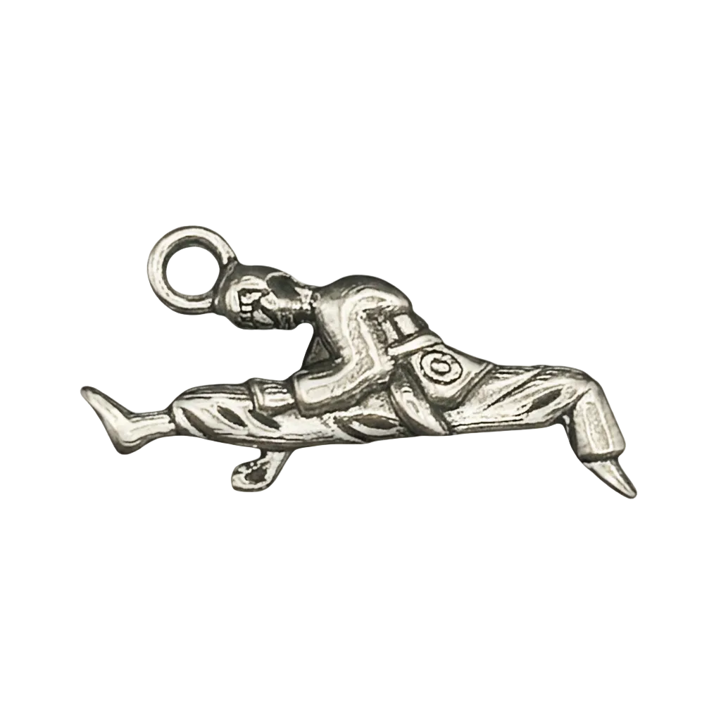 close-up of a silver-tone charm shaped like a martial artist doing a flying kick on a black background