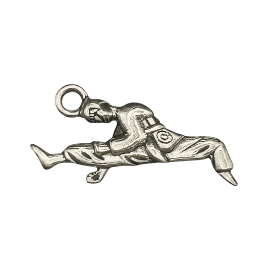 close-up of a silver-tone charm shaped like a martial artist doing a flying kick on a black background