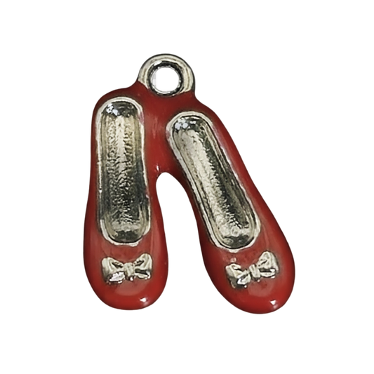 close-up of a small charm shaped like red ballet flats with silver details and bows