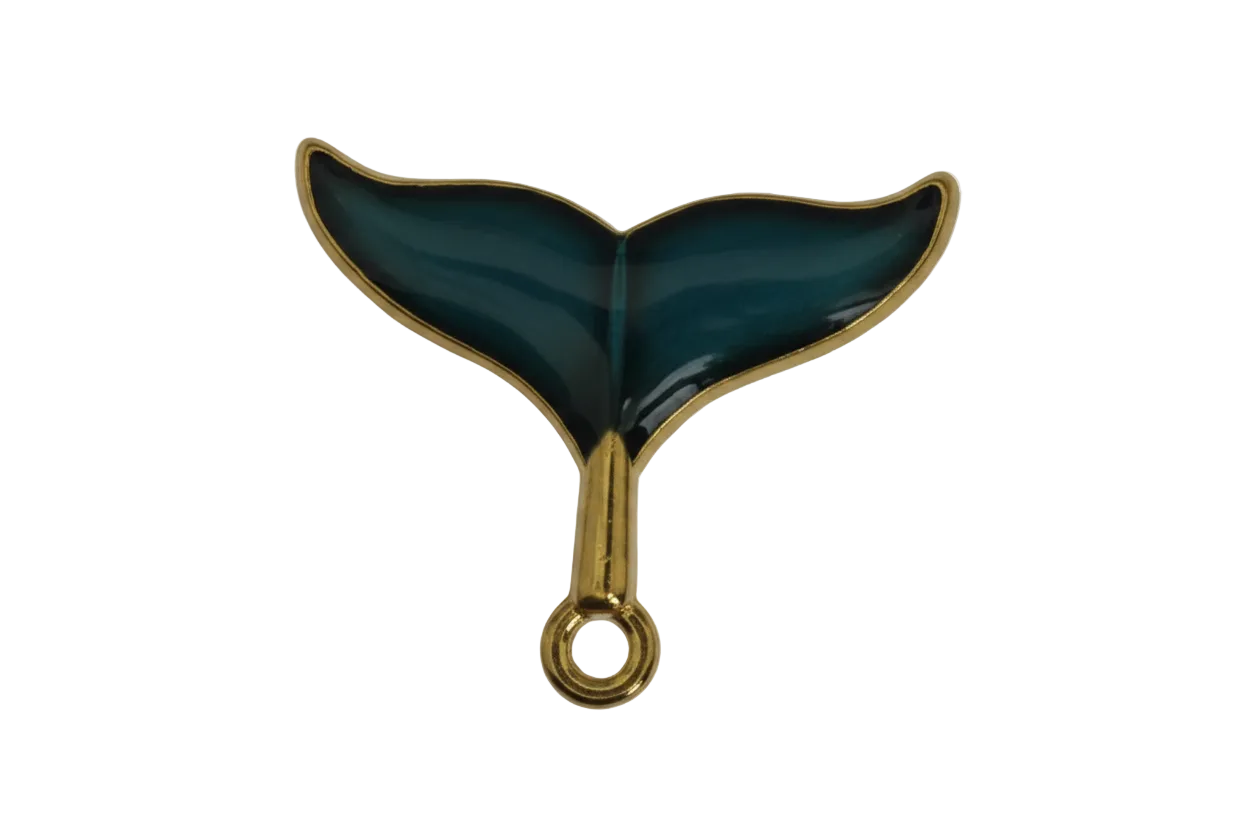 close-up of dark teal whale tail charm with gold edges on a black background