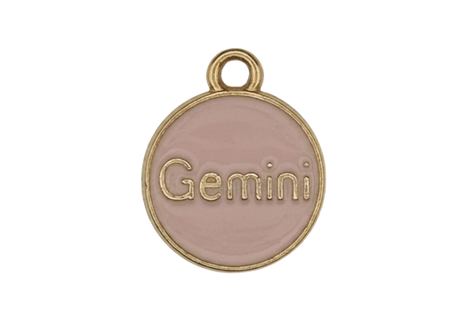 close-up of pink enamel round charm with the word Gemini and gold-tone border