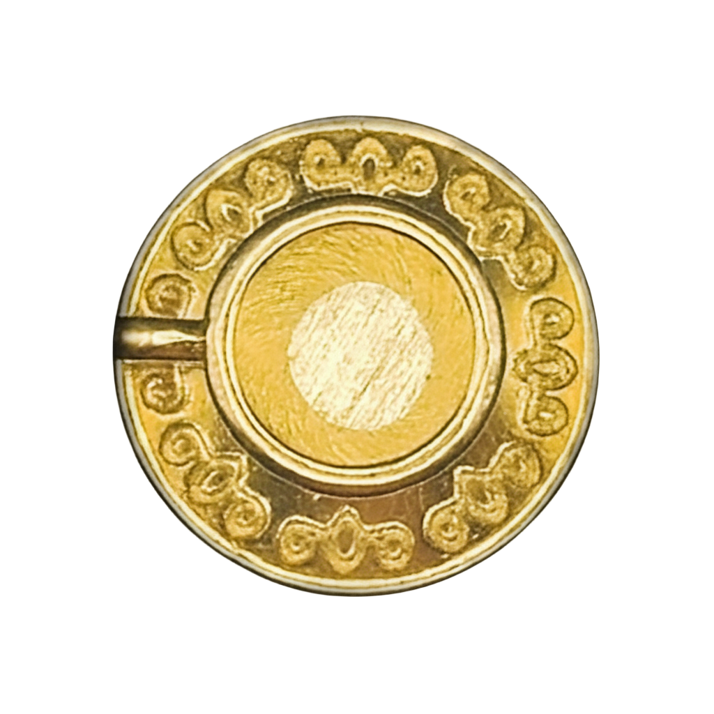 close-up of small round gold-tone engraved coin charm on black background
