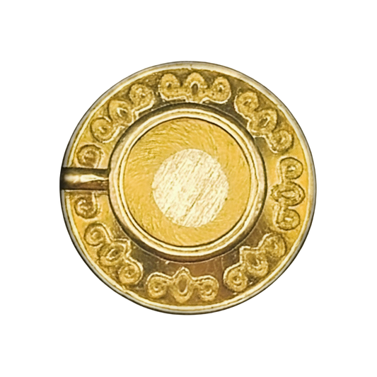 close-up of small round gold-tone engraved coin charm on black background