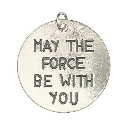 Close-up of round silver disc charm engraved 'MAY THE FORCE BE WITH YOU'.
