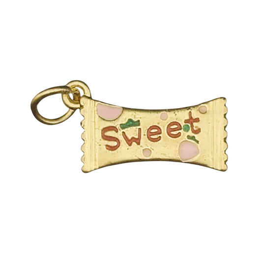 close-up of gold-tone candy wrapper charm reading “Sweet” with pink and green enamel on a black background