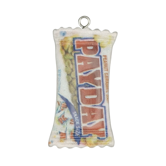 close-up of a miniature candy bar wrapper charm with 'PAYDAY' text, on a black background